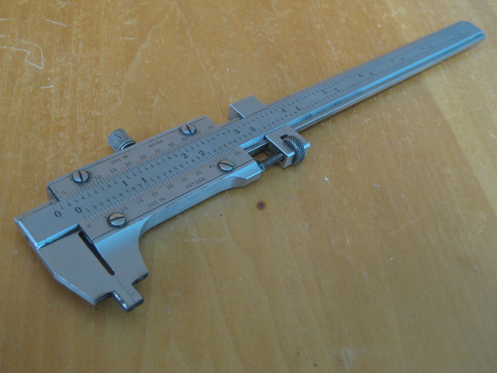 Vernier calipers on a light wooden surface.