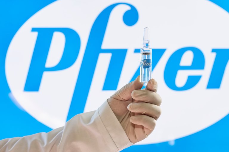 A Uzbekistani doctor holds up a dose of the Pfizer COVID-19 vaccine in front of the company's logo.