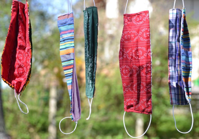 Multicolored masks for COVID-19 hanging from clothesline.