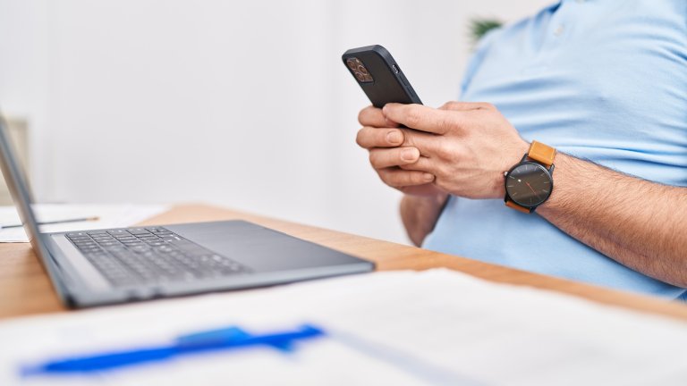 Worker using laptop and smartphone at office